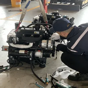 Close-up view of a technician assembling a gasoline engine, using tools to connect components in a factory workshop.