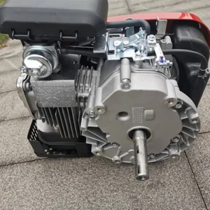 Side rear view of a single-cylinder gasoline engine, placed on outdoor concrete pavement.