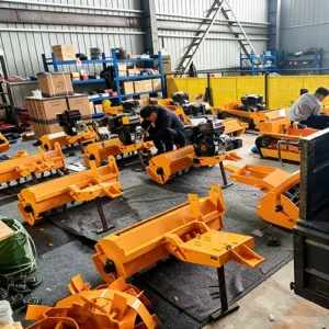Top view of workers assembling yellow tracked lawn mower components, including cutting decks and engine units, in a factory workshop.