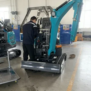 Side view of a technician inspecting a teal mini excavator, checking hydraulic and control systems in a factory workshop.
