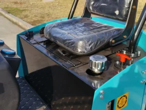 Close-up of a black operator seat, hydraulic tank cap, and red emergency stop valve on a blue mini excavator.