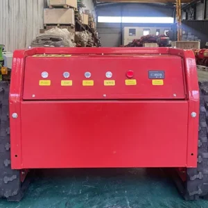 Front view of a red "Shenlong" remote-controlled lawn mower in a factory workshop, showcasing its control panel and robust chassis.