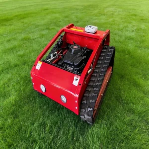 Front side view of a red remote-controlled lawn mower with robust tracks and a gasoline engine, on a lush green grass field.