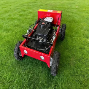 Front side view of a red remote-controlled lawn mower with a robust gasoline engine and rugged wheels, on a lush green grass field.
