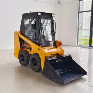 Front side view of a yellow wheeled skid steer loader with enclosed cab and black bucket attachment, in a bright indoor showroom.