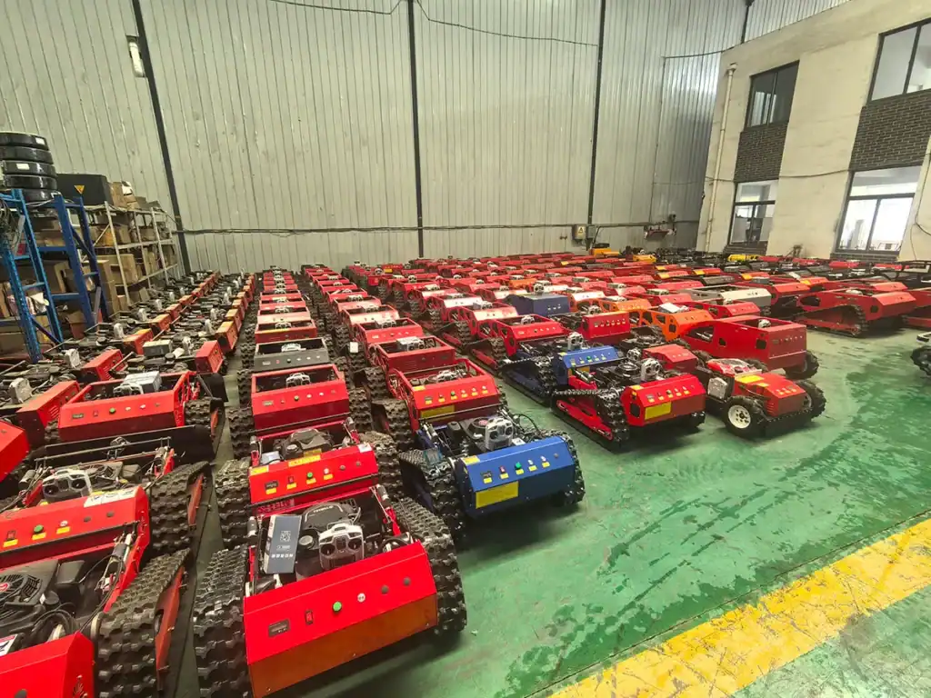 Large inventory of tracked remote-controlled lawn mowers neatly arranged in a factory workshop, ready for shipment.