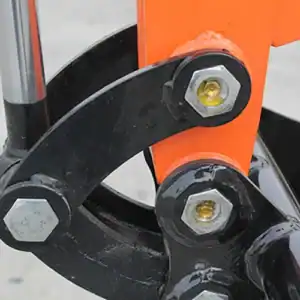 Close-up of a mini excavator's boom hinge joint, showing heavy-duty bolts, grease fittings and reinforced structure for construction machinery.