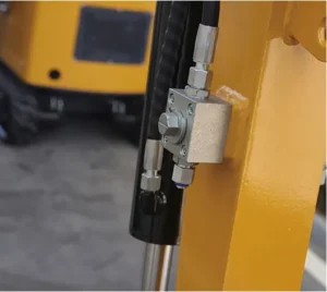 Close-up of hydraulic control valve block mounted on yellow mini excavator boom