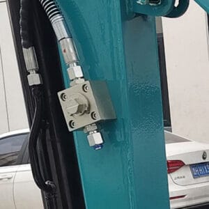 Close-up of control valve mounted on teal mini excavator boom with fittings