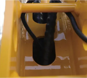 Close-up of protected hydraulic hoses and fittings inside yellow mini excavator boom