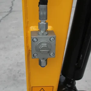 Close-up of mini excavator boom with hydraulic valve, pressure fitting and yellow metal arm