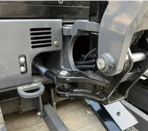 Close-up of mini excavator's boom pivot joint, hydraulic cylinder and metal linkage