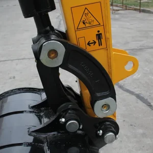 Close-up of mini excavator bucket hinge joint with warning labels and heavy-duty bolt connections