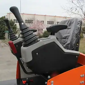 Close-up of a mini excavator's cabin joystick controls, featuring ergonomic handles, safety levers and operator seat for construction equipment.