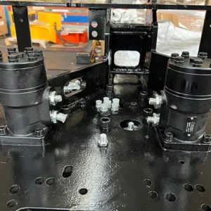 Close-up of mini excavator chassis showing dual hydraulic motors, bolted connections and base plate