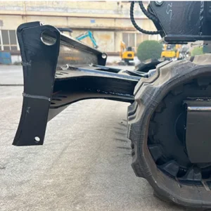 Close-up of mini excavator's dozer blade, hydraulic arm and heavy-duty rubber track in factory yard
