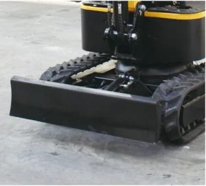 Close-up of mini excavator dozer blade and rubber tracks on concrete surface