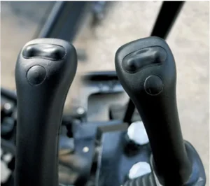 Close-up of mini excavator's dual joystick control handles with ergonomic buttons