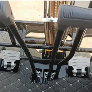 Close-up of mini excavator's foot pedals and joystick levers with quilted cabin floor mat