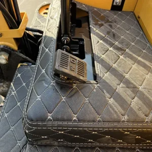 Close-up of mini excavator's foot pedal control with textured surface and quilted cabin floor mat