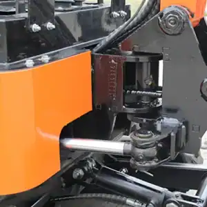 Close-up of a mini excavator's hydraulic cylinder and swing mechanism, showing hydraulic lines, pivot joints and reinforced structure for construction equipment.