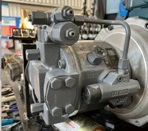 Close-up of grey hydraulic main pump assembly for mini excavator with fittings and labels