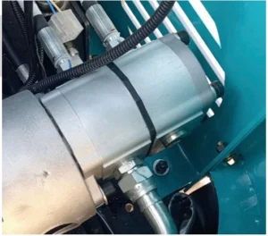 Close-up of silver hydraulic pump assembly on teal mini excavator with hoses and connectors
