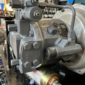 Close-up of mini excavator main hydraulic pump with valves, fittings and hydraulic lines in factory setting