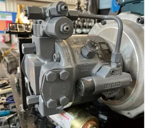 Close-up of mini excavator main hydraulic pump with bolts, valves and QR code label