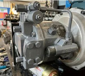 Close-up of mini excavator's main hydraulic pump with bolts, valves and QR code label