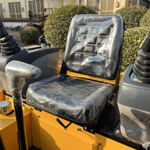 Close-up of mini excavator's operator seat with protective plastic cover and dual joystick control levers