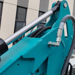 Close-up of teal mini excavator boom cylinder, protective hoses and metal fittings