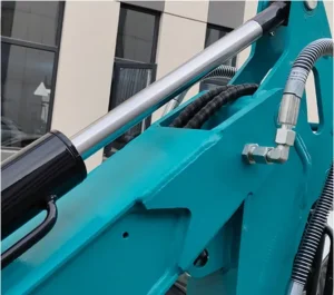 Close-up of teal mini excavator boom hydraulic cylinder, hose fittings and reinforced arm